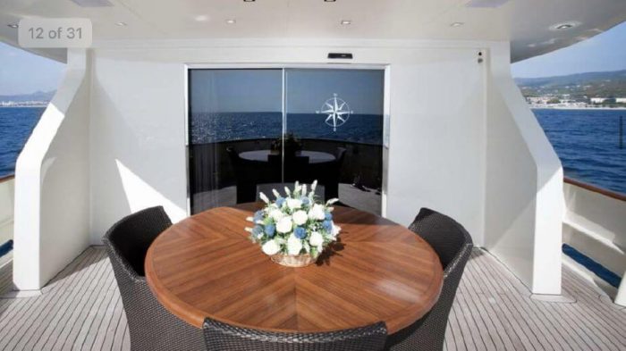 Wooden table with seating and flowers on Benetti 95 yacht deck